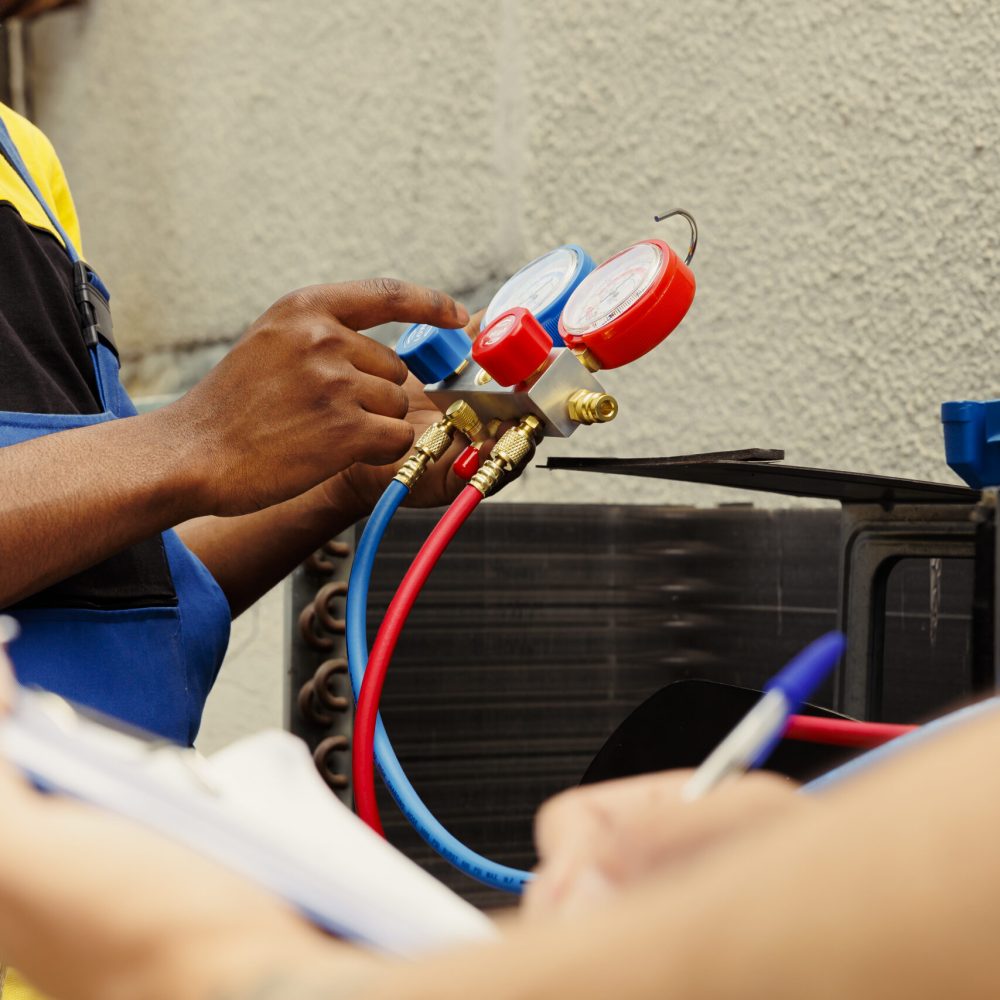 Professional workers assigned to do air conditioner check, refilling freon. Expert repairmen team using ac gauges vacuum pump to skilfully measure the pressure in HVAC system